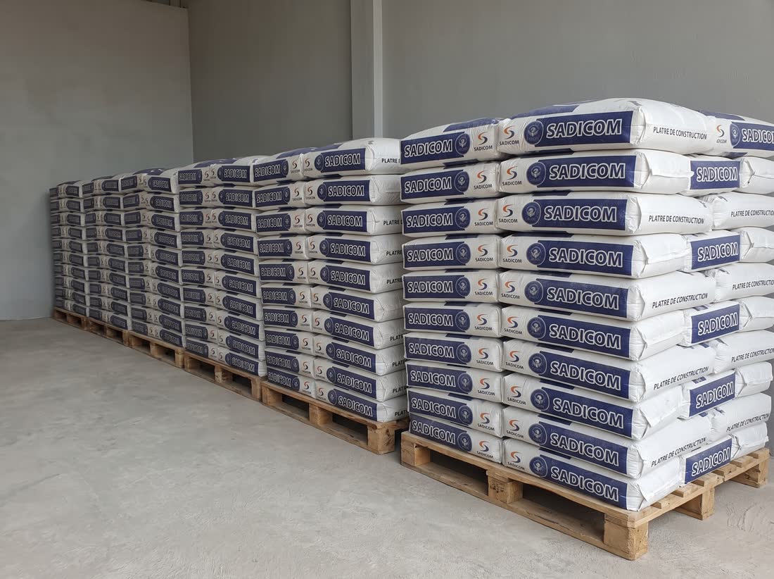 Rangée de palettes de sacs de plâtre de construction 40 kg à la marque Sadicom au dépôt